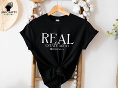 Elevate your real estate game with our Custom Real Estate Agent T-shirt. This personalized real estate tee, featuring your custom location, is the perfect gift for any dedicated realtor. Ideal for agent marketing attire, it combines professionalism and style, making it a must-have for your wardrobe. See more of our designs in our REAL ESTATE section: https://www.etsy.com/shop/unicraftydesigns/?etsrc=sdt&section_id=49847464 CHECK OUT MORE FOR OUR UNIQUE DESIGNS: unicraftydesigns.etsy.com SIZE & MATERIAL * Unisex T-shirt * Runs true to size * 100% cotton (fibre content may vary for different colours) HOW TO ORDER: *Please make sure to check all photos in the listing. *Choose your shirt colour and size. *Click add to cart. You can follow the same steps to add more items in your cart. *Click " Real Estate Shirts, Shirt Colour, Realtor Gifts, Baseball Shirts, Different Colours, Estate Agent, Real Estate Agent, Add To Cart, Custom Shirts