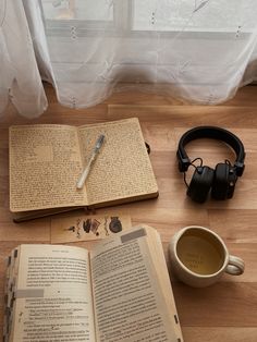 an open book with headphones and a cup of coffee on the floor next to it