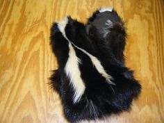 a black and white furry animal laying on top of a wooden floor with it's tail curled up