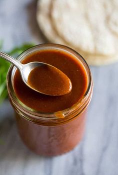 a spoon full of sauce sitting on top of a jar