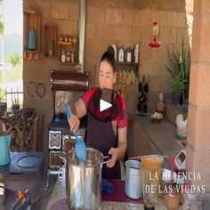 a woman in an outdoor kitchen cooking food on the stove and stirring it with a ladle