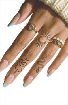 a woman's hand with tattoos on it and two rings in the middle of her fingers