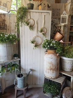 a room filled with lots of potted plants next to a white door and shelves