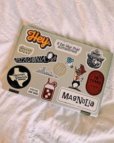 a laptop covered in stickers sitting on top of a bed