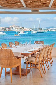 an outdoor dining area overlooking the ocean with boats in the water and tables set up