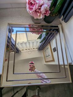 a person taking a selfie in front of a mirror with pink flowers on it