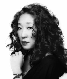 a black and white photo of a woman with long curly hair wearing a watch on her wrist