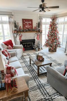 a living room decorated for christmas with red and white decorations on the fireplace, couches, coffee table, and tree