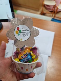 a person holding up a cup filled with candy