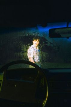 a man is seen through the windshield of a car as it drives by in the dark