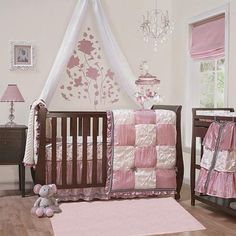 a baby crib with pink and white bedding in a nursery room next to a chandelier