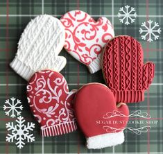 four decorated cookies with mittens, gloves and snowflakes on a plaid tablecloth