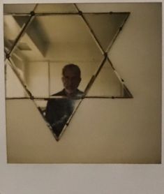 a man is seen in the reflection of a mirror with an inverted design on it