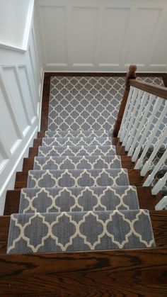 the stairs are decorated with gray and white rugs, along with wooden handrails