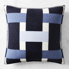 a black and blue pillow with white trim on the bottom is sitting against a wall