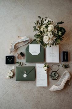 the wedding stationery is laid out on the floor next to shoes and bouquets