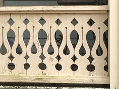 an old white wooden bench with decorative ironwork on the top and bottom, in front of a house