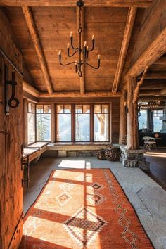 the sun shines through the windows in this rustic living room with wood paneling and chandelier