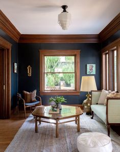 a living room with blue walls and wood trimmings on the ceiling, two couches in front of a coffee table