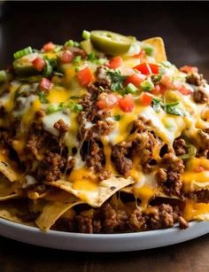 a white plate topped with nachos covered in cheese and toppings on top of a wooden table