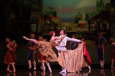 a man and woman dancing on stage with other dancers