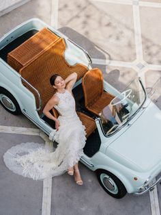 a woman in a white dress standing next to a car