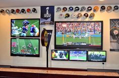 several televisions are mounted on the wall in a sports themed room with football helmets hanging above them