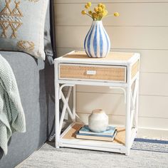 a blue and white vase sitting on top of a small table next to a bed