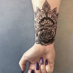 a woman's hand with a black and white rose tattoo on the left wrist