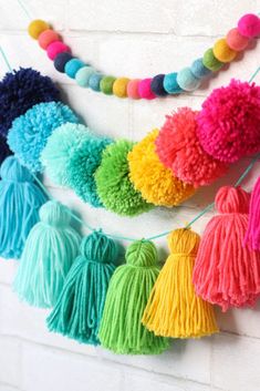 multicolored tasselled pom - poms hanging on a brick wall