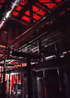 the inside of a building with pipes and red light coming from it's ceiling