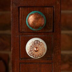 the door knobs on this wooden cabinet are decorated with copper and turquoise accents,