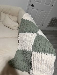 a couch with a green and white blanket on top of it next to a door