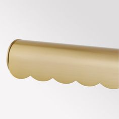 a gold curtain rod with scallops on the top and bottom, hanging from a white wall