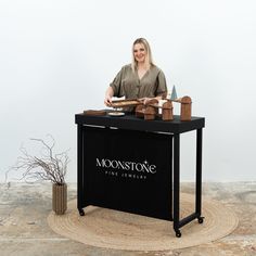 a woman sitting at a table with a book in front of her on the moon stone logo