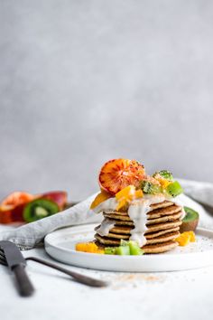 a stack of pancakes with fruit and whipped cream on top, sitting on a white plate