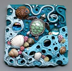 a sea turtle sitting on top of a blue piece of art with shells and seashells