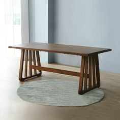 a wooden table sitting on top of a hard wood floor next to a white rug