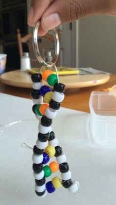 a person is holding a keychain made out of beads