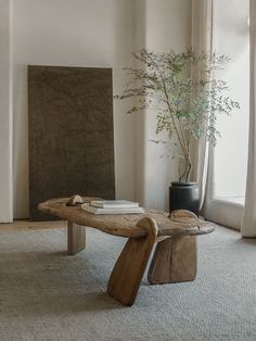 a wooden table sitting in front of a window next to a vase with a plant on it