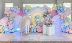 a white horse standing in front of a backdrop with pastel colors and balloons on it