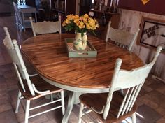 a wooden table with chairs around it and a vase full of flowers on the table