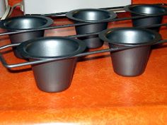 six black bowls are sitting on a rack next to a white box and an orange counter