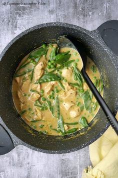 a pan filled with chicken and green beans in sauce on top of a wooden table