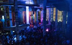 a large group of people standing around in a room with blue lights on the walls