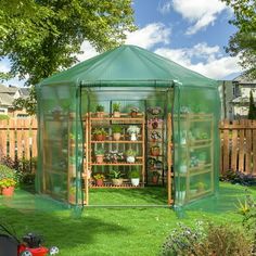 a small green house sitting on top of a lush green field next to a garden