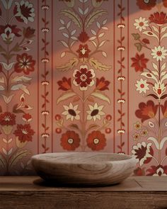 a bowl sitting on top of a wooden table in front of a floral wallpaper