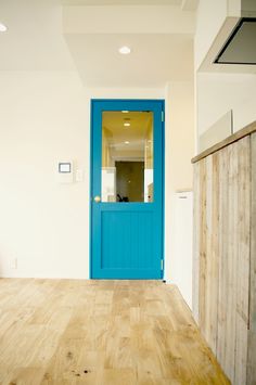 an empty room with a blue door and wooden floor