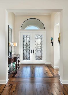 an entryway with wooden floors and two glass doors on either side of the door