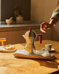 a person is pouring coffee into a cup on a table in front of a window